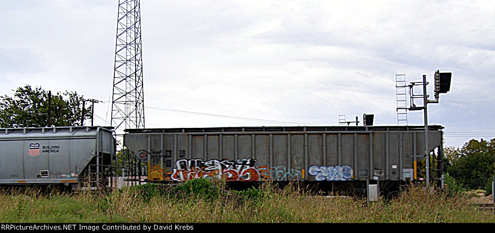 Somewhere under all that grafitti is a UP covered hopper.....